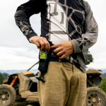 Pilote tout-terrain plaçant un personal locator beacon ACR ResQLink View RLS dans sa pochette de ceinture de protection.