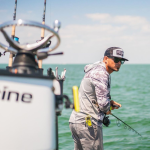 Pêcheur pêchant depuis un bateau avec un personal locator beacon ACR ResQLink View RLS fixé solidement à sa taille.