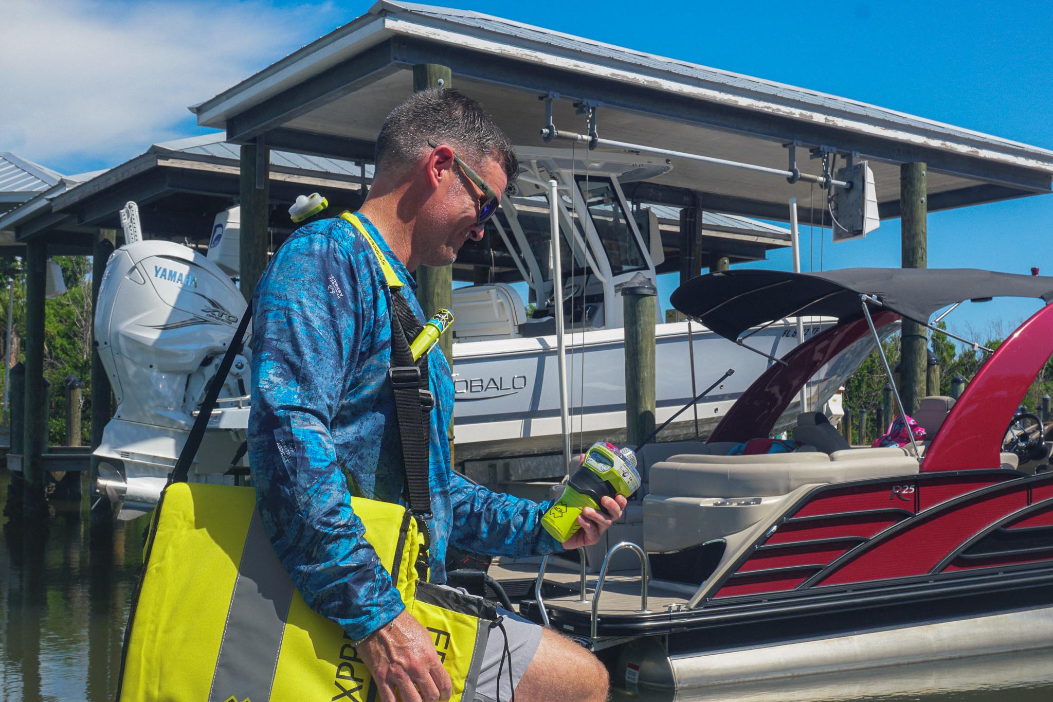 Boater carrying a GlobalFix V6 EPIRB and ditch bag aboard a boat