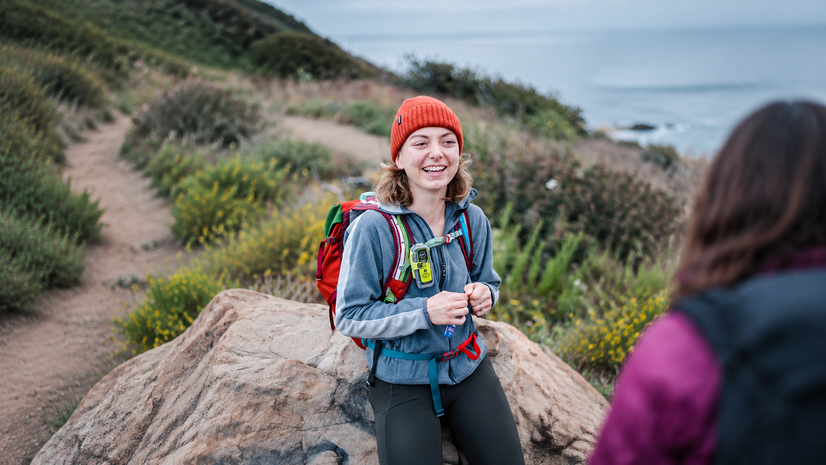 Hiker carrying an ACR ResQLink 400 Personal Locator Beacon on a remote coastal trail