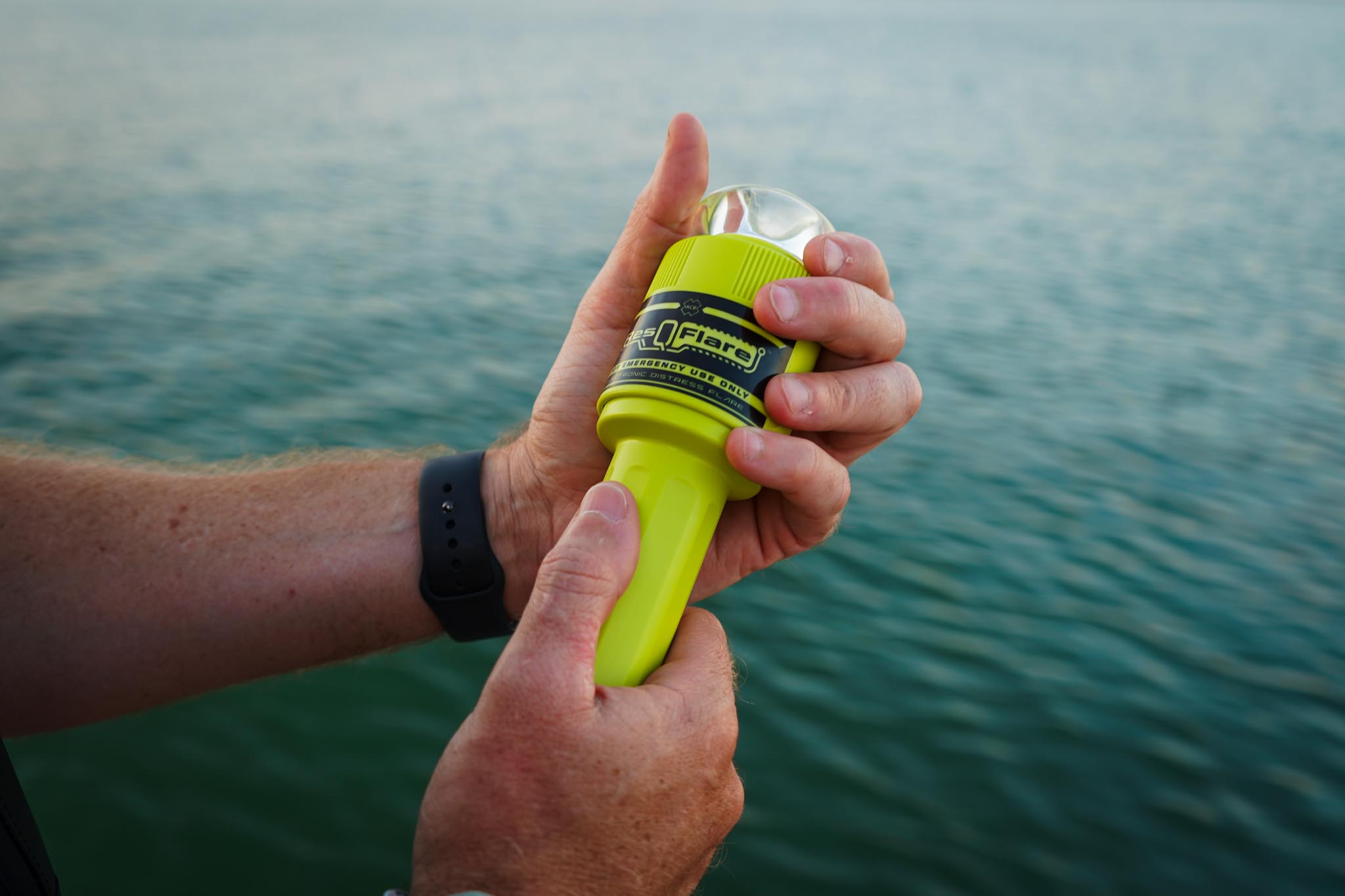 ACR ResQFlare electronic distress light held in two hands beside the water in daylight