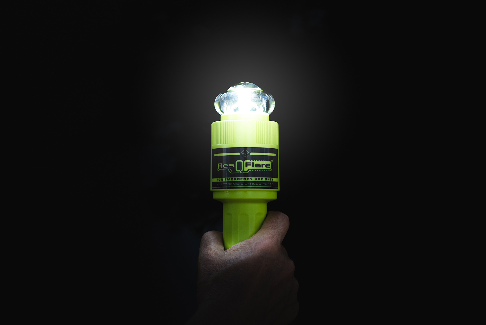 ACR ResQFlare electronic distress light held in a hand, illuminating the darkness